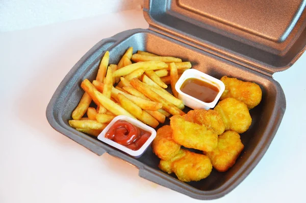 Lezzetli patates kızartması, tavuk nugget, sos, kese kağıdı, beyaz arka plan. Deli gibi yiyorum. Yemek servisi..