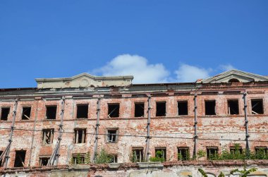 Pencereli terk edilmiş eski bir binanın tuğla cephesi.