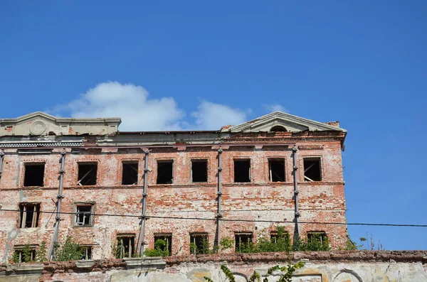 Fachada de tijolo de um edifício antigo abandonado com janelas. Imagens De Bancos De Imagens