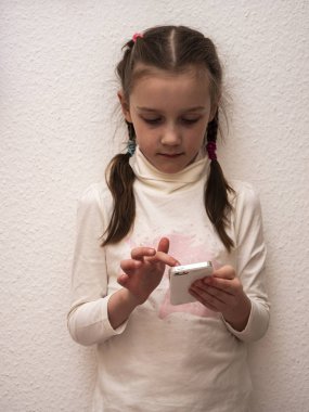 Küçük kız çocuk telefon tableti kullanıyor. Oyun oynuyor.