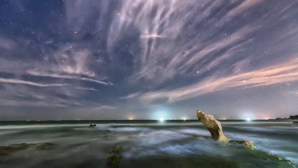 A praia à noite com uma rocha em direção às estrelas e galáxia cintilante — Fotografia de Stock