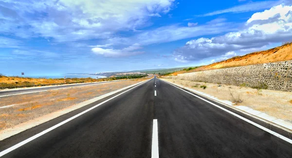 Lange Autobahn durch sonnigen Wüstenwind unter dramatischem Himmel Sommertag — Stockfoto