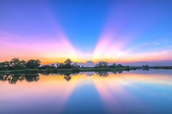 Stralen van zonsondergang langs de rivier wanneer de zon aan de horizon ondergaat — Stockfoto