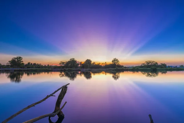 Strålar av solnedgång längs floden när solen går ner till horisonten — Stockfoto