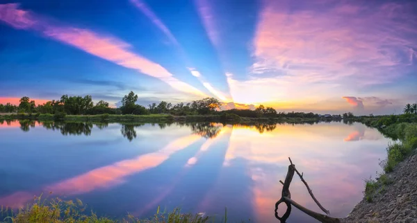 Rayons de coucher de soleil le long de la rivière quand le soleil se couche à l'horizon — Photo