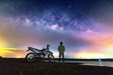 Dong Nai, Vietnam - 19th Şubat 2018: Samanyolu gece gökyüzü ve Dong Nai, Vietnam topraklarda yakınındaki kırsal kesimde dramatik gökyüzünde bir motorbyke konumu olan bir adam silüeti.