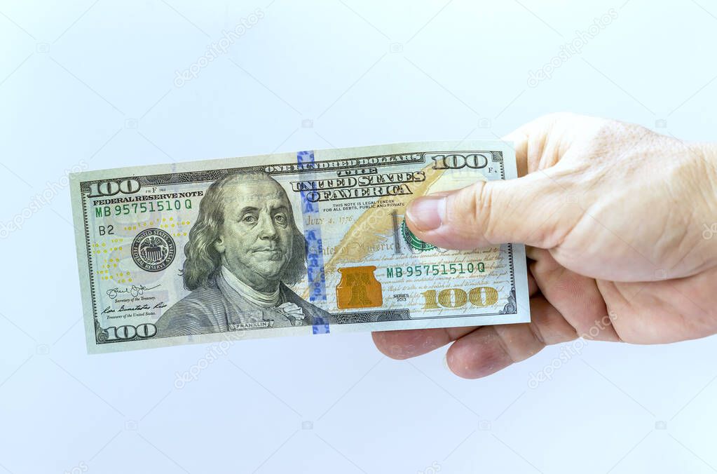 Man's hand takes or gives one hundred US dollars. Business and finance concept.