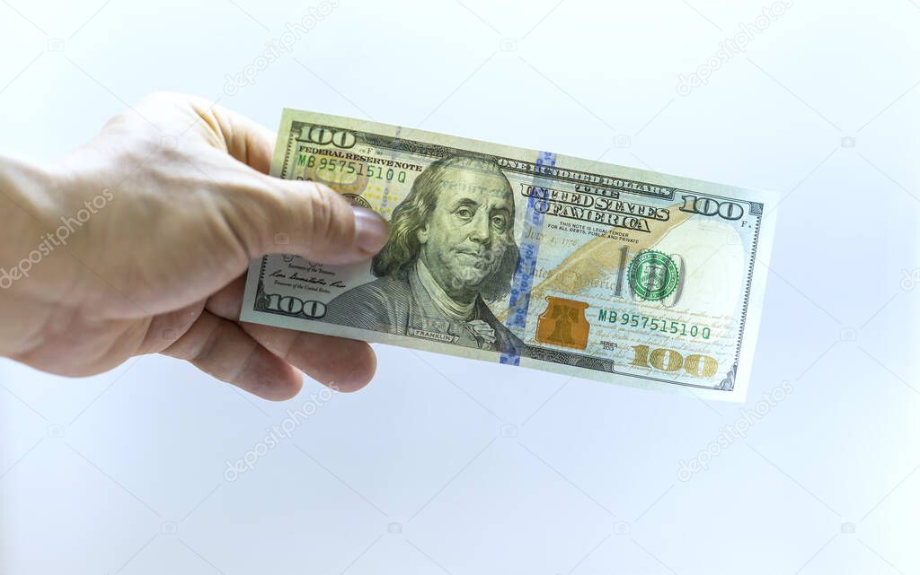 Man's hand takes or gives one hundred US dollars. Business and finance concept.