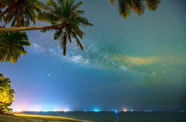 Hindistan cevizi palmiye ağacı silueti ve Samanyolu ile gece yarısı deniz manzarası güzel bir yaz gecesinde gökyüzünde. Uzun pozlama fotoğrafı.
