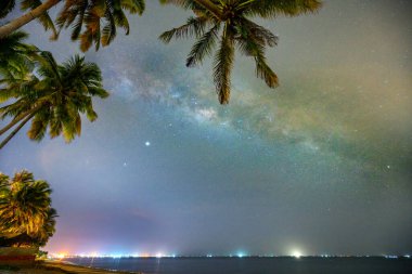 Hindistan cevizi palmiye ağacı silueti ve Samanyolu ile gece yarısı deniz manzarası güzel bir yaz gecesinde gökyüzünde. Uzun pozlama fotoğrafı.