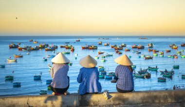 Mui Ne, Vietnam - 4 Mart 2020: Vietnam yakınlarındaki küçük bir köyde şafak vakti balıkçı teknesini bekleyen Vietnamlı bir grup kadın.