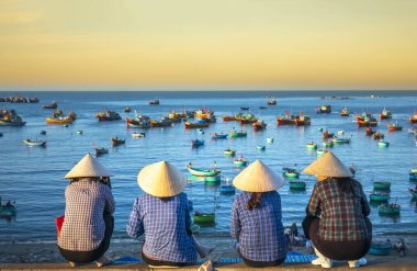 Mui Ne, Vietnam - 4 Mart 2020: Vietnam yakınlarındaki küçük bir köyde şafak vakti balıkçı teknesini bekleyen Vietnamlı bir grup kadın.