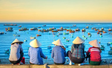 Mui Ne, Vietnam - 4 Mart 2020: Vietnam yakınlarındaki küçük bir köyde şafak vakti balıkçı teknesini bekleyen Vietnamlı bir grup kadın.