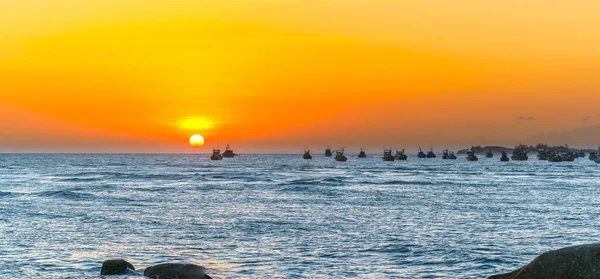 Sea landscape at sunset when the sun shines down the horizon shines bright yellow, beneath the fishing boats anchored peacefully