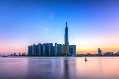 Ho Chi Minh City, Vietnam - 25 Şubat 2020: Ho Chi Minh City, Vietnam 'daki en ekonomik gelişmeyi gösteren gökdelenlerle nehir kenarındaki kentsel alanda renkli günbatımı manzarası