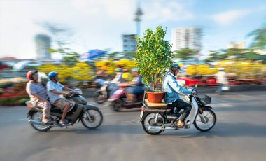 Ho Chi Minh Şehri, Vietnam - 22 Ocak 2020: Vietnamlılar motosiklet sürerken arkasında çiçek saksısı olan insanlar, ev dekorasyonu için çiçekler alarak Ho Chi Minh, Vietnam 'da yeni yıla hoş geldiniz
