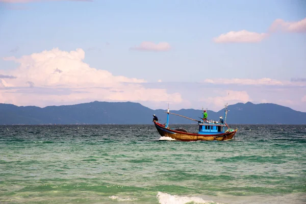 Güneşli bir günde bir arka planda dağların okyanusa balıkçı teknesi