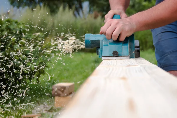 El ile elektrikli planya ahşap tahta üzerinde çalışma marangoz kapatın