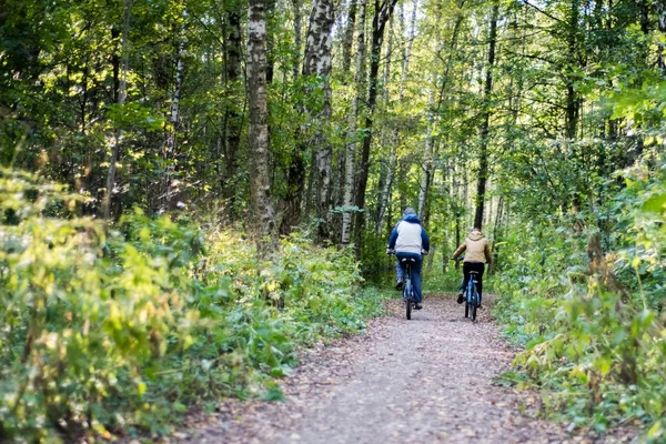 İki bicyclists sonbahar ormanda binmek. Çocuk ile baba