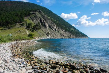 Mavi Gökyüzü bulutlu deniz yüzeyi üzerinde. Güneşli bir gün görünümünde kayalık sahil