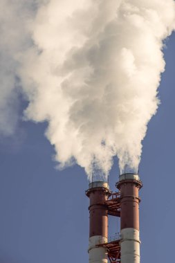 Endüstriyel fabrika borular üzerinde mavi gökyüzü güneş, duman. Ekoloji sorunları