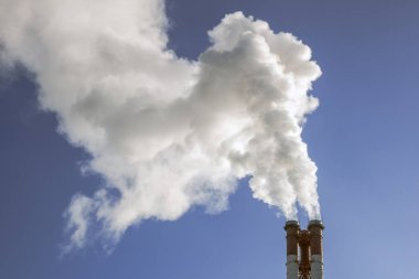 Endüstriyel fabrika borular üzerinde mavi gökyüzü güneş, duman. Ekoloji sorunları