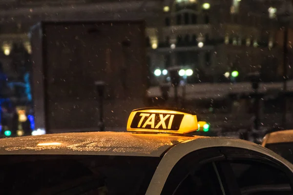 Освещённый знак такси на крыше такси в ночном городе — стоковое фото