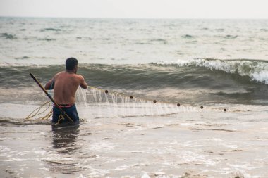 Goa, Hindistan - 23 Şubat 2017: gün batımı anda balık ağı kullanarak denizde balık yakalamak balıkçı