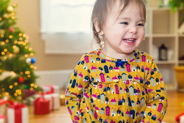 Meisje glimlachend voor de kerstboom — Stockfoto