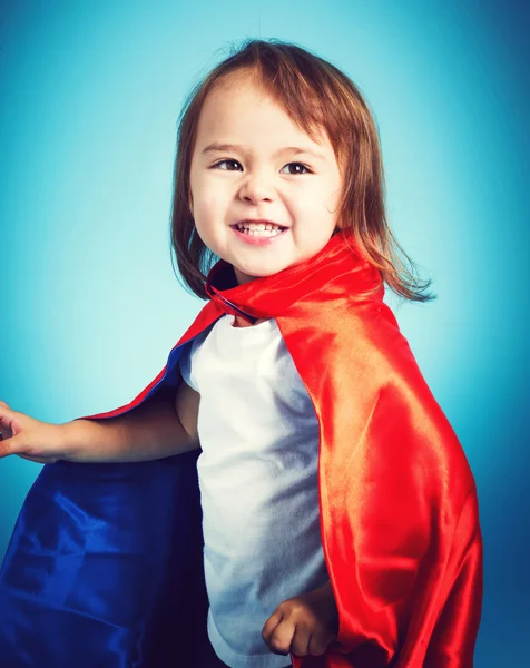 Menina da criança jogando em uma capa de super herói — Fotografia de Stock