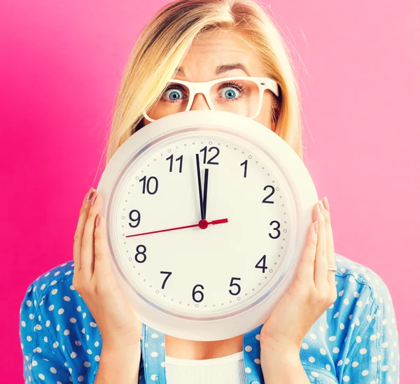 Mujer sosteniendo reloj mostrando casi doce — Foto de Stock