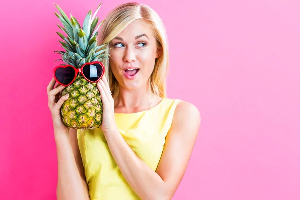 Kvinna anläggning ananas med solglasögon — Stockfoto