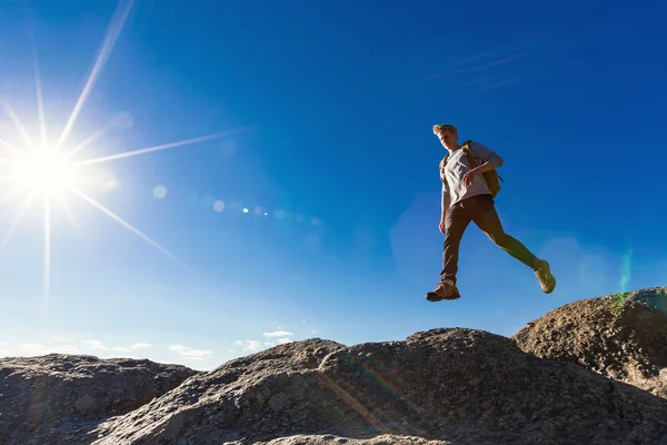 Чоловік стрибає через прогалину на горі — стокове фото