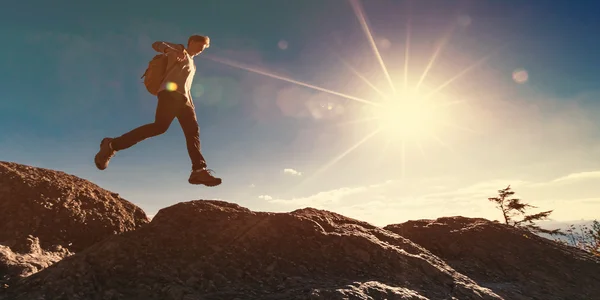 Hombre saltando sobre la brecha en la montaña — Foto de Stock