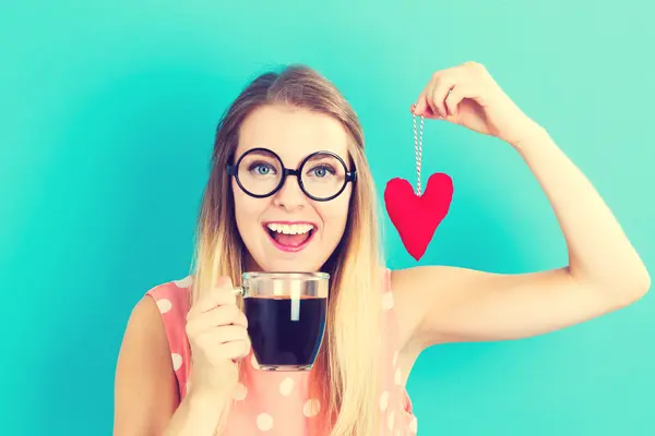 Mulher bebendo café com almofada de coração — Fotografia de Stock