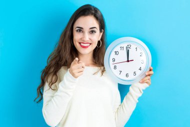 Saati yaklaşık 12 gösteren tutan kadın