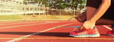 Kadın koşucu ayakkabıları bir stadyum yolda bağlama