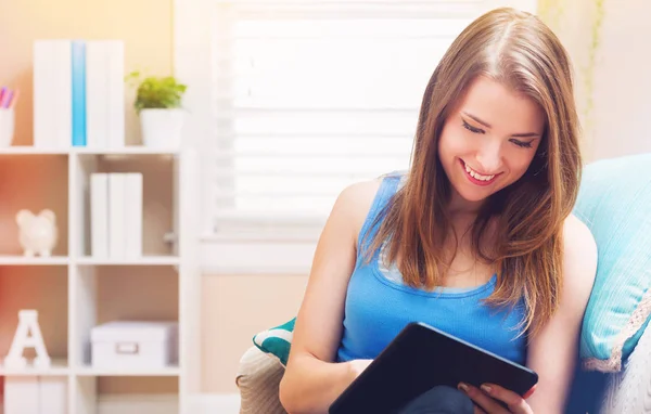 Happy young woman reading an e-book on her couch — Stock Photo, Image