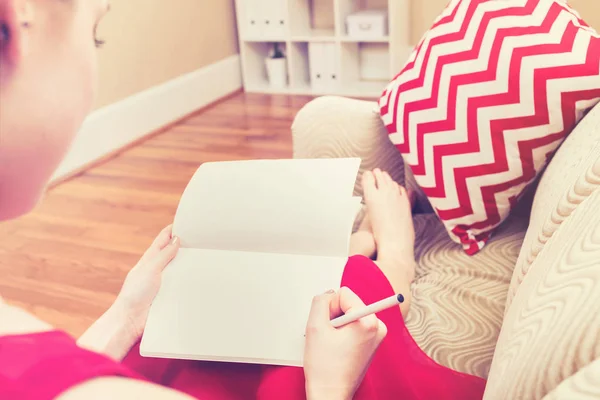 Jonge vrouw schrijven in haar notitieblok — Stockfoto