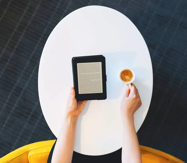 Digital book reader and coffee on oval table