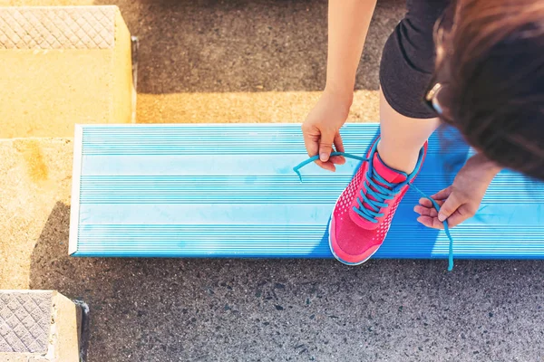 Female jogger tying her shoes on the bleachers — Stock Photo, Image
