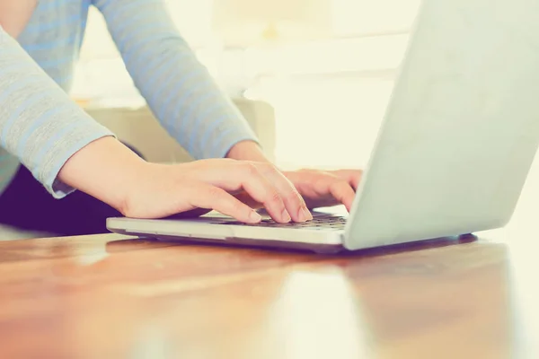 Vrouw die werkt op een laptop in een lichte kamer — Stockfoto