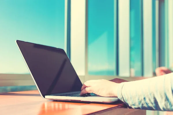 Vrouw die werkt op een laptop in een lichte kamer — Stockfoto