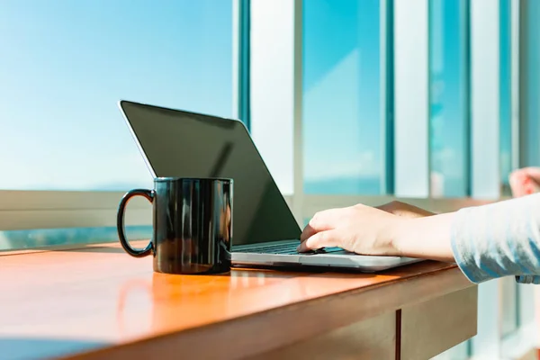 Vrouw die werkt op een laptop in een lichte kamer — Stockfoto