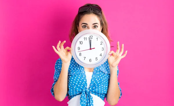 Mujer sosteniendo reloj mostrando casi 12 — Foto de Stock