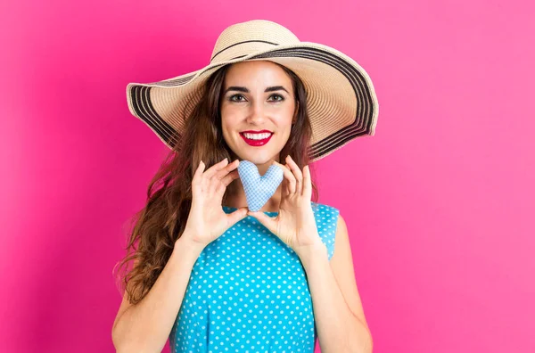 Happy young woman holding a heart cushion — Stock Photo, Image