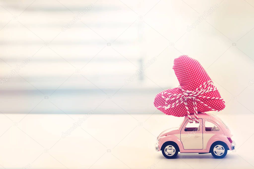Miniature pink car carrying heart cushion 