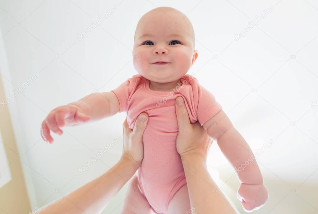 Happy infant baby girl being held up in the air