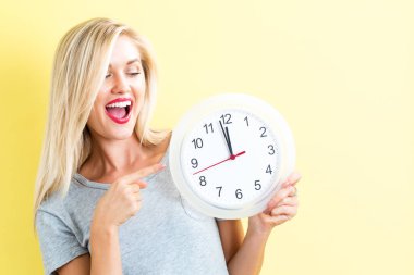  Saati yaklaşık 12 gösteren tutan kadın