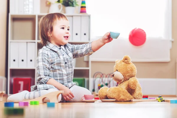 Menina feliz jogando com seu ursinho de pelúcia — Fotografia de Stock